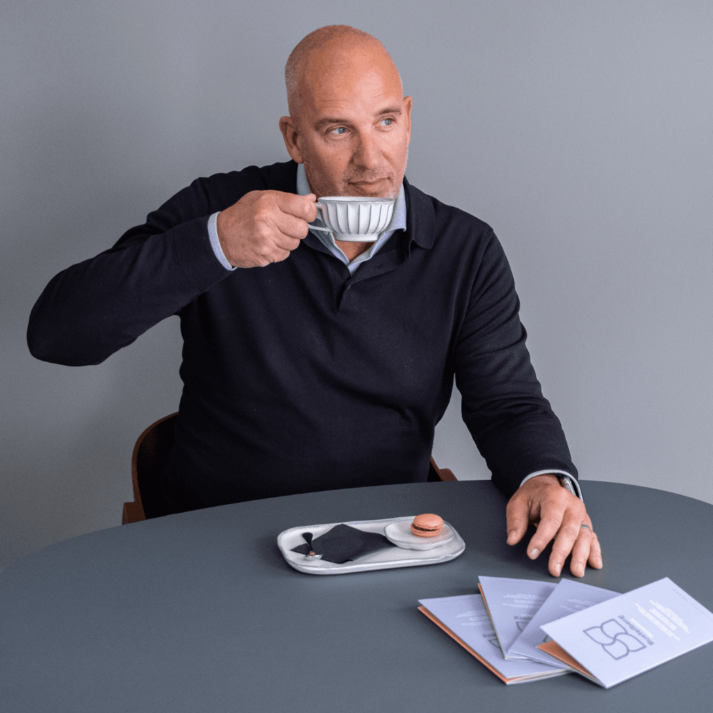 Man drinkt koffie aan tafel met documenten voor zich