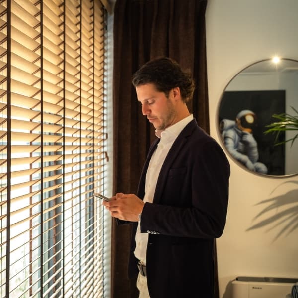 Adviseur kijkt op zijn telefoon bij het raam van het kantoor